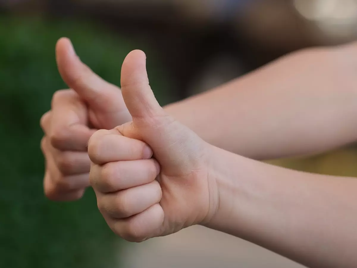 A man in a blue shirt is pointing with his index finger. The image has a light background.